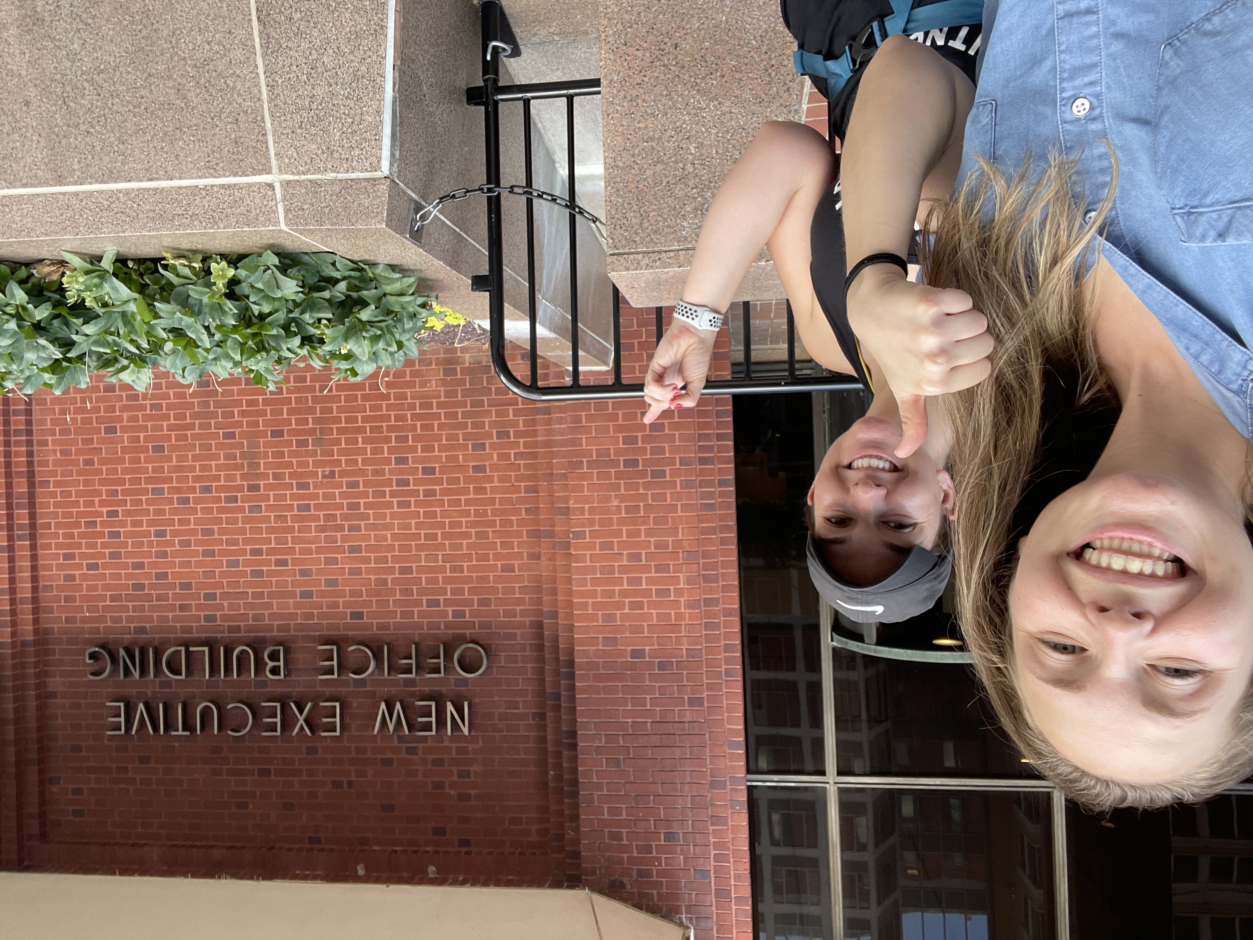 Two LBJ students smile in front of a red brick government building 