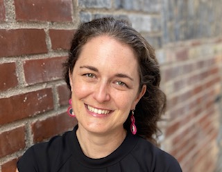photo of woman smiling against a brick wall 