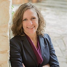 Headshot of Lisa Kirsch leaning against a brick wall 