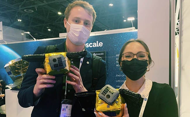 Alyssa Goessler and a colleague with a model of a machine to help clean up the Earth's orbit