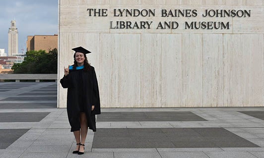 Charlotte Gorman (MGPS '20), in cap and gown, on the plaza in front of the LBJ Library