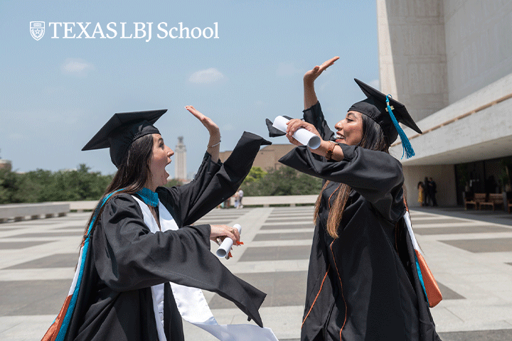Two 2022 grads high five on the plaza after their graduation ceremony