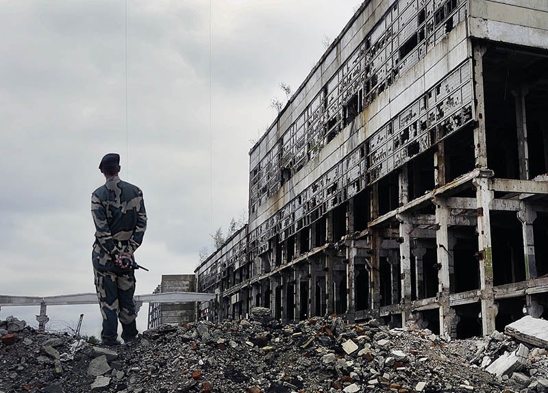 Soldier standing on rubble near a bombed-out building