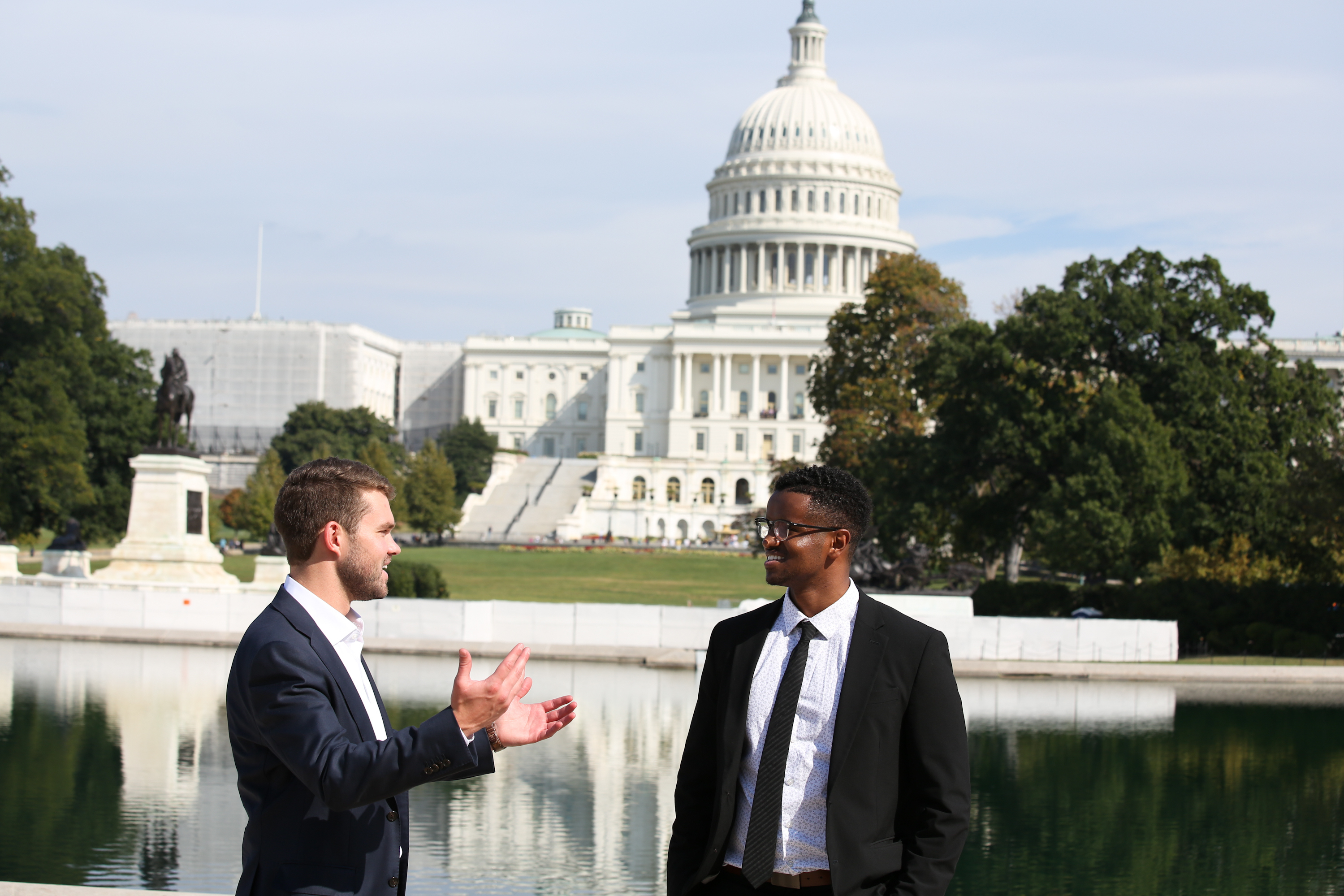 Two LBJ students in suits engage in conversation in front of the US Capitol 