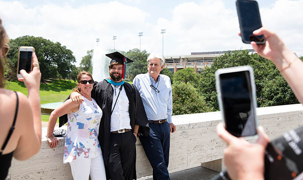 An LBJ graduate poses with his family in front of the fountain. Credit: Callie Richmond