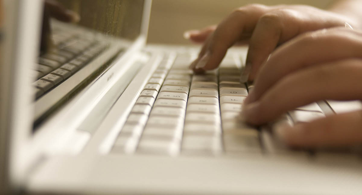 Close-up of an adult's hands typing on a computer keyboard