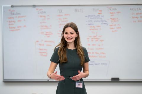 Student presents in an LBJ Classroom with whiteboard full of writing in the background