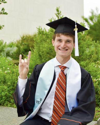 Incoming LBJ School student Cooper Slack posing on campus in his graduation attire.