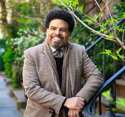 Headshot of Darrick Hamilton outside, leaning on staircase railing