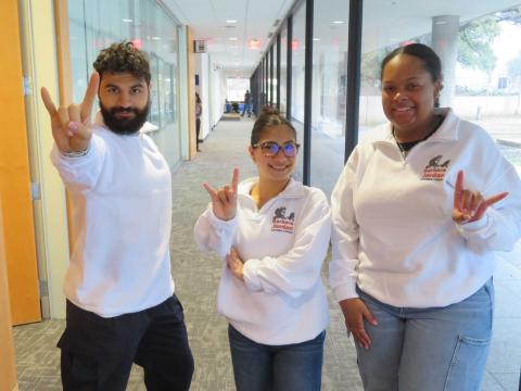 BJNF chairs wearing matching white BJNF pullovers, throwing up UT hookem sign