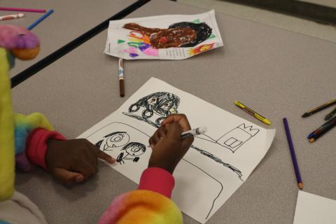 child drawing a picture and a completed coloring book page of Barbara Jordan