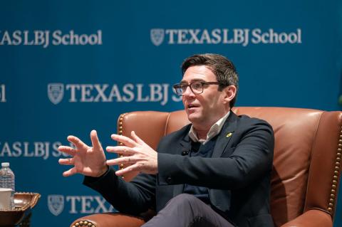 Andy Burnham in front of LBJ School banner gesturing while speaking to the audience