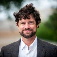 Photo of a man outside wearing gray blazer and white button up