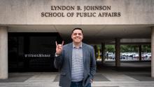 LBJ alumni, Steven Santoyo, in front of LBJ School hook 'em