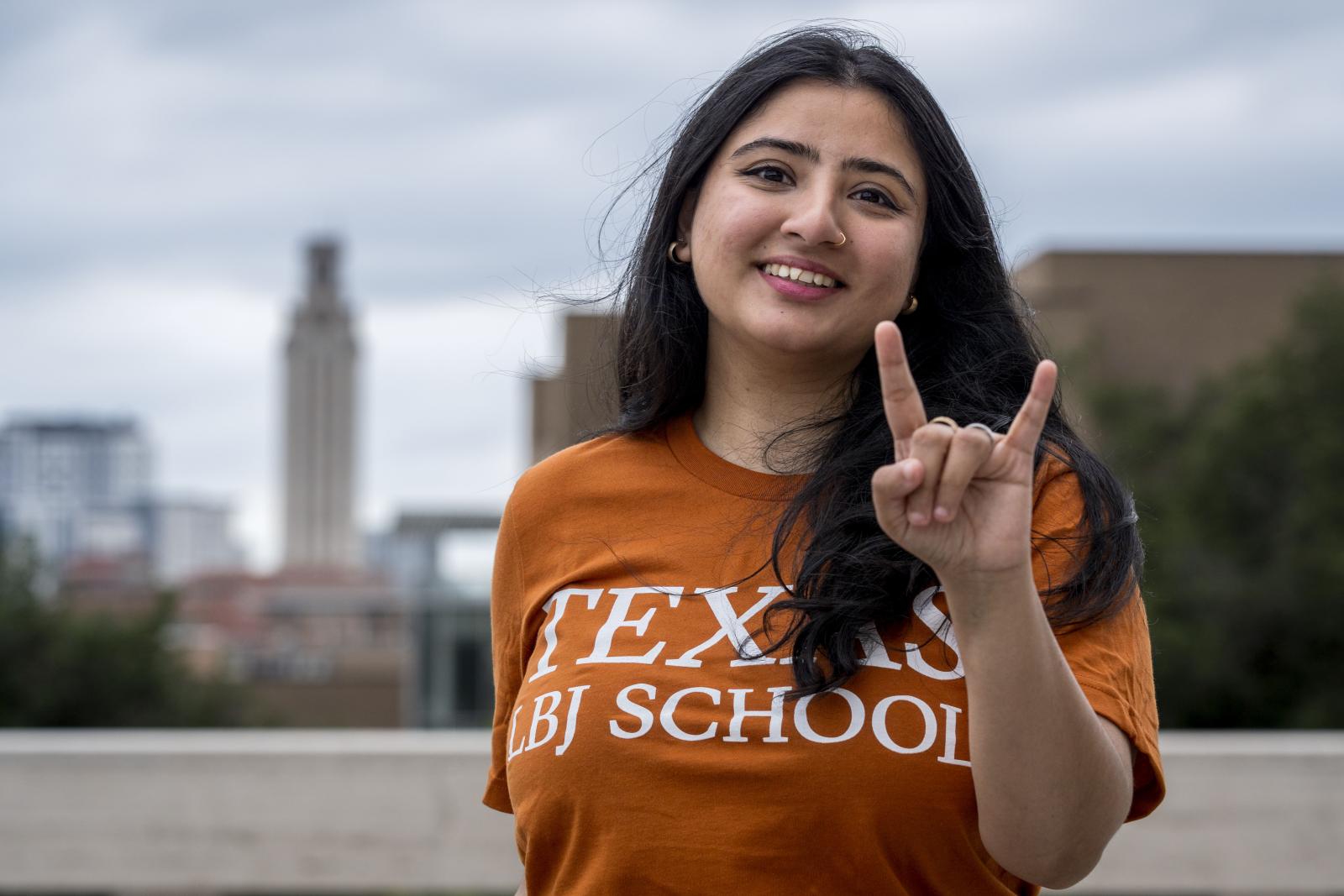 Rania Sohail posing with a hookem hand sign in front of the UT Tower