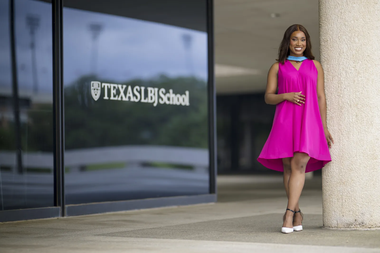 Student speaker Morgan Brown in a pink dress by the LBJ School