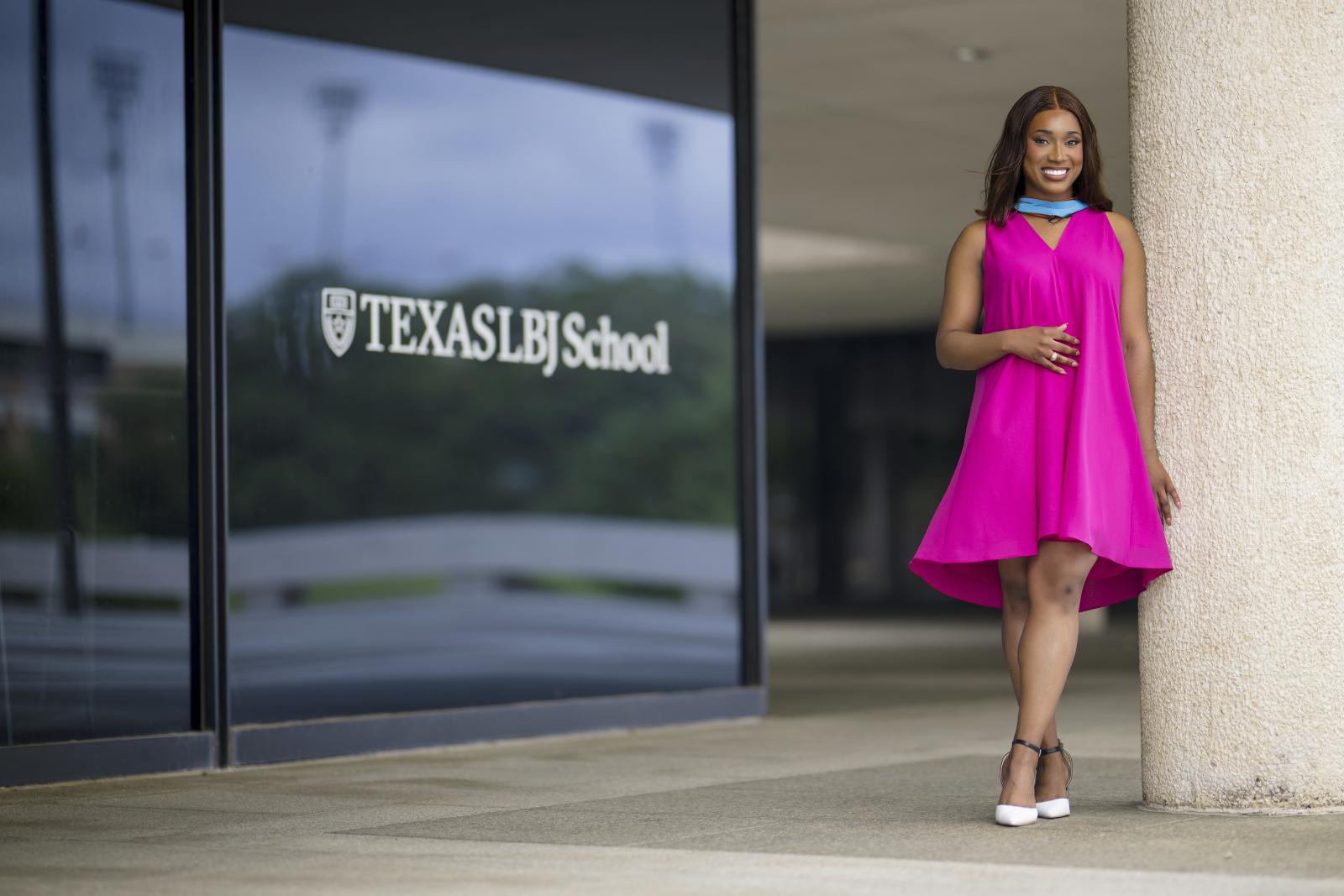 Student speaker Morgan Brown in a pink dress by the LBJ School