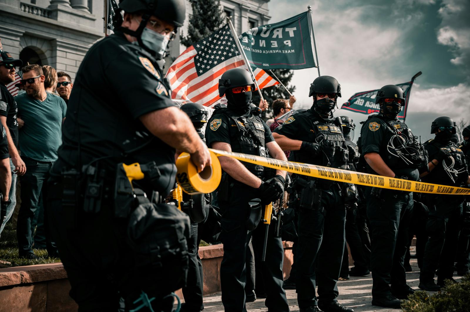 Police officers are posted at a political rally and sectioning off areas with caution tape.