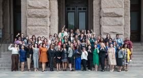 Students of the LBJ Women's Campaign School pose with the hook 'em hand sign on the steps of the famous UT tower.