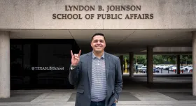 LBJ alumni, Steven Santoyo, in front of LBJ School hook 'em