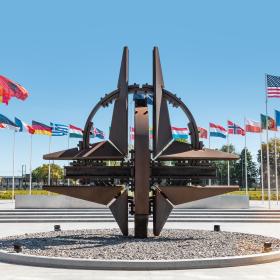 Image shows the member countries flags waving outside of NATO Headquarters. 