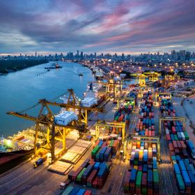 The image shows shipping containers and a cargo ship at port. 