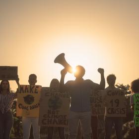 photo of a group of people protesting, backlit at sunset