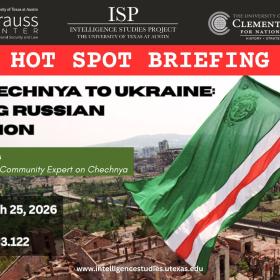 On the righthand side of this image, an older man waves the flag of the Chechen Republic of Ichkeria — colored green, white, and red -- waves over beige-colored, destroyed buildings can be seen in the background, and a crowd of what appears to be the city’s inhabitants flows through the street below.