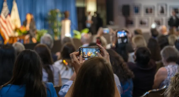 The audience member takes a photo of a speaker onstage