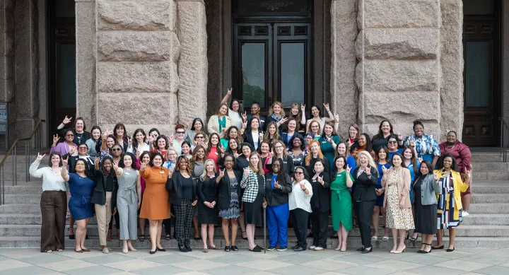 Students of the LBJ Women's Campaign School pose with the hook 'em hand sign on the steps of the Texas Capitol.