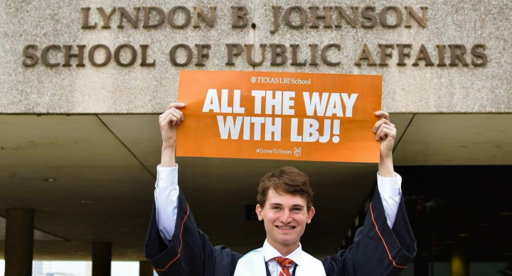 Incoming LBJ Student Cooper Slack poses with an "all the way with LBJ" mailer in his undergraduate regalia.
