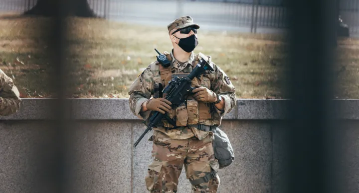 A soldier in a mask looking up at the Capitol