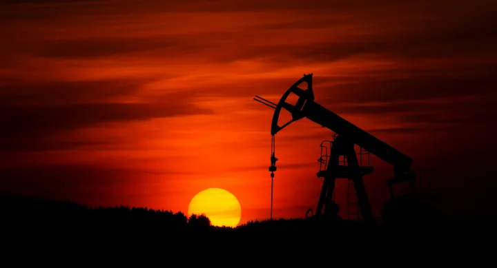 An oil rig sits at sunset.