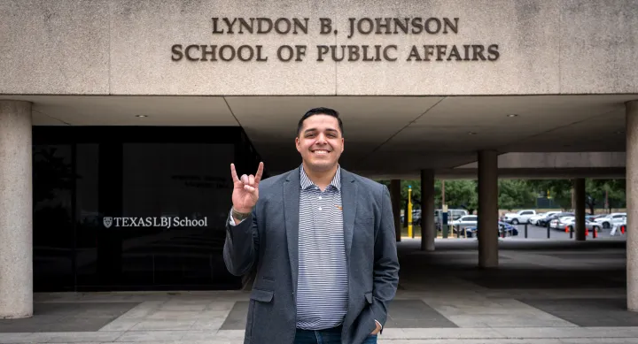 LBJ alumni, Steven Santoyo, in front of LBJ School hook 'em