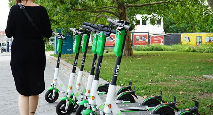 Woman walking past a row of Lime scooters — credit Vince Jacob Fozkow